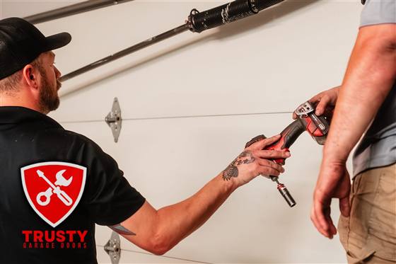 Technician repairing a garage door roller bracket with an impact driver in Plano, TX