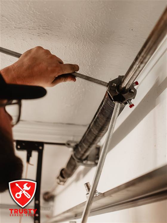 Close-up of a technician winding a garage door torsion spring in Dallas, TX